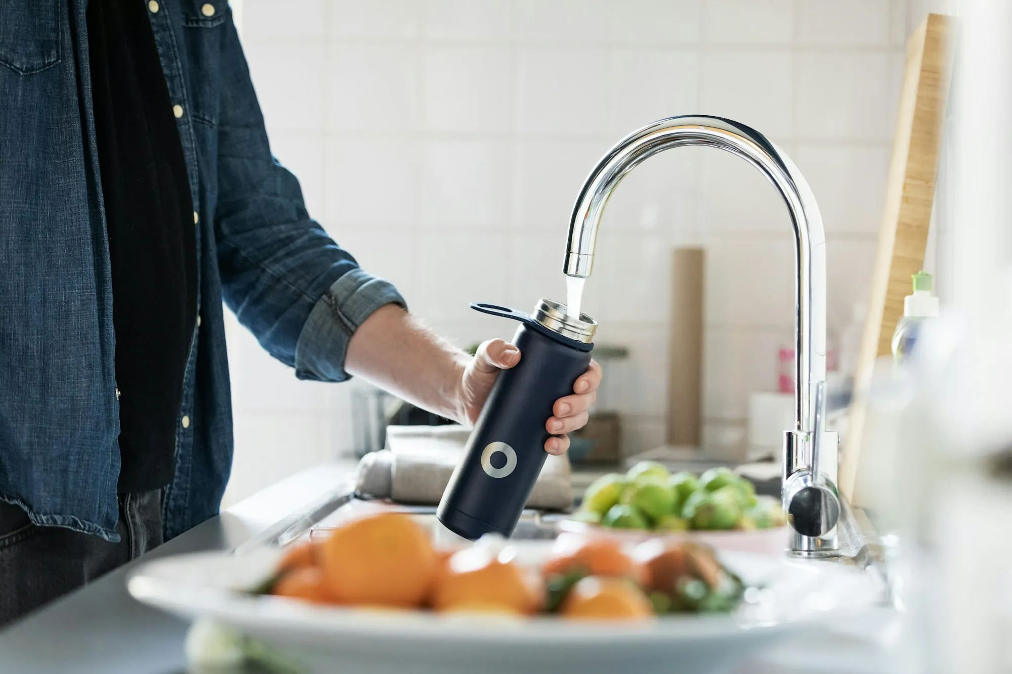 How our Aliso Viejo water service works Person filling a bottle at a stainless kitchen faucet