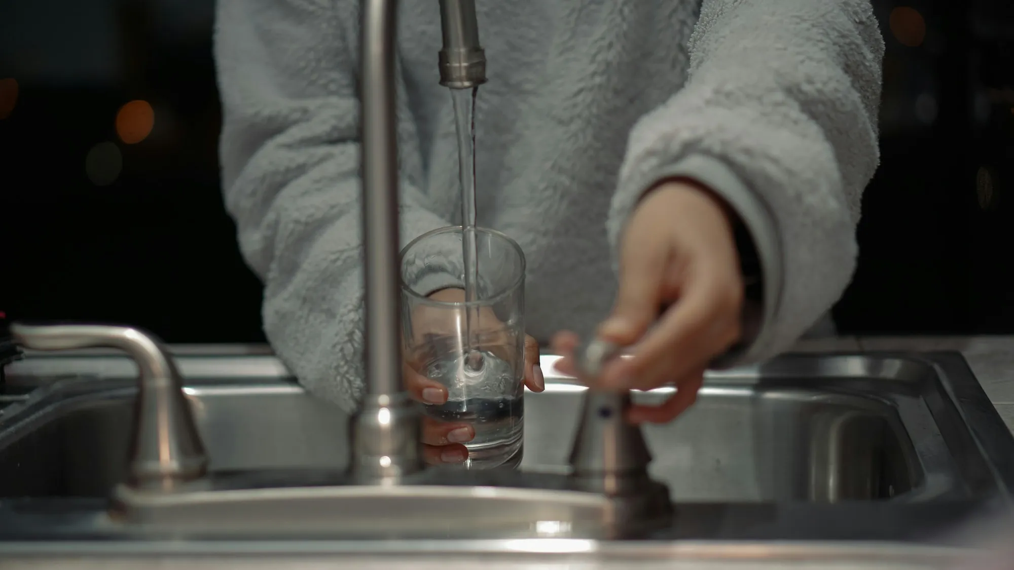 Reverse osmosis systems in Aliso Viejo Person filling a glass at a kitchen faucet
