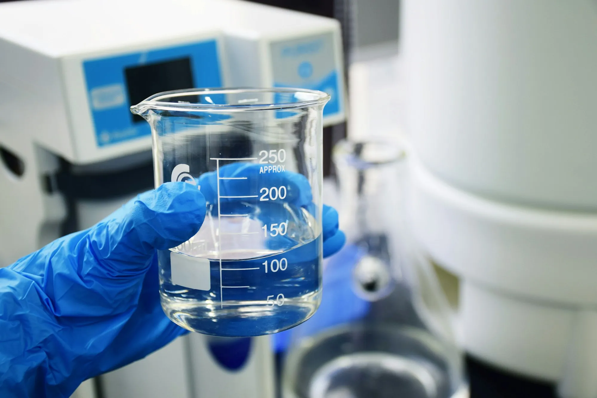 Water testing and analysis in Aliso Viejo Gloved hand holding a beaker of water in a lab