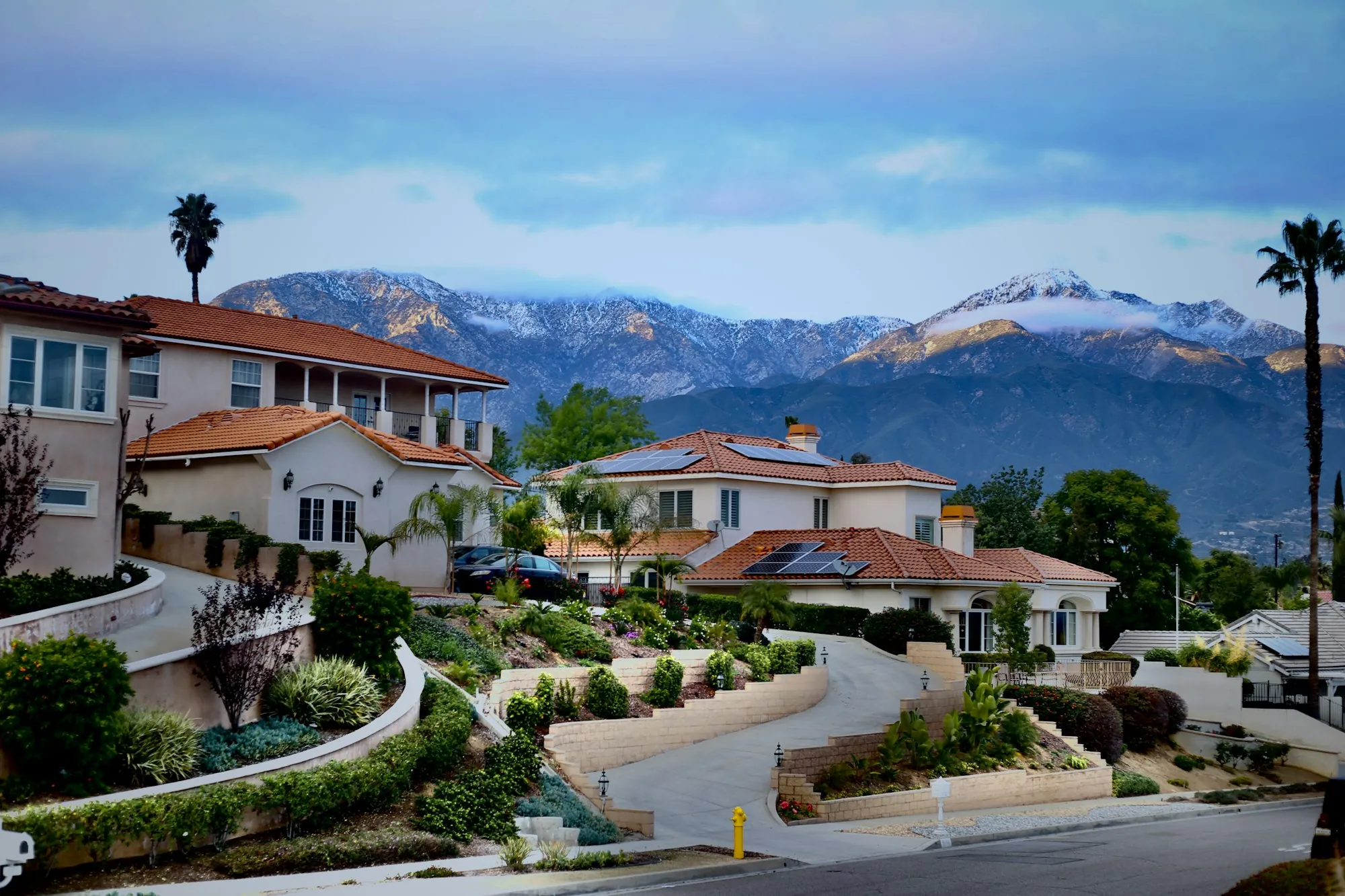 Hillside homes along a curving street with mountains behind