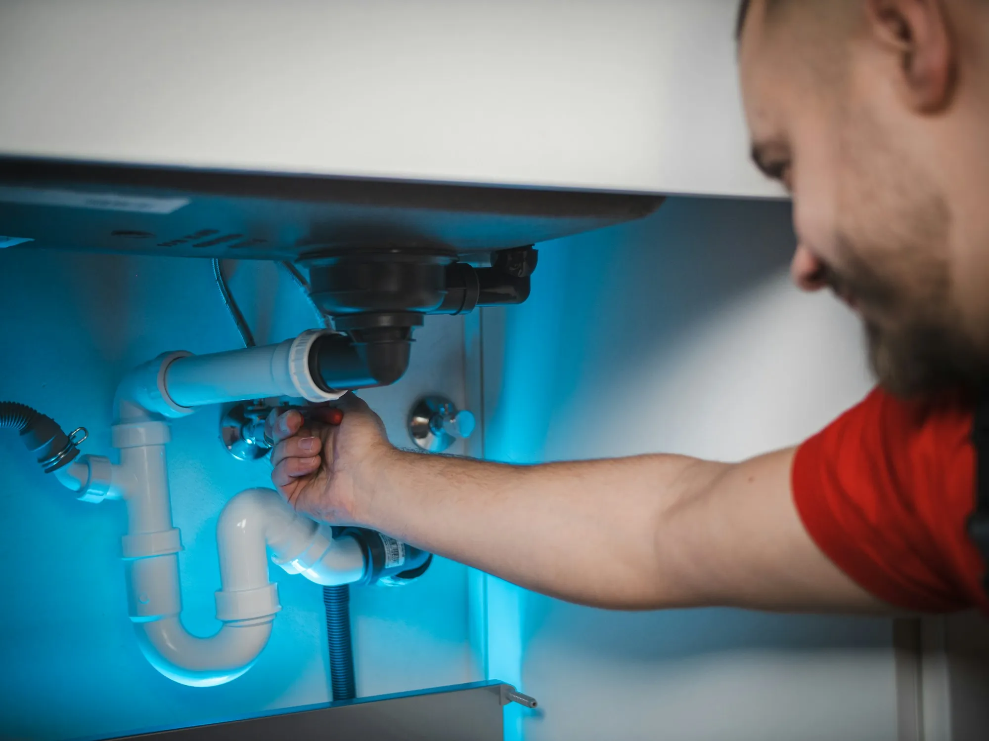 Plumber connecting pipes under a kitchen sink