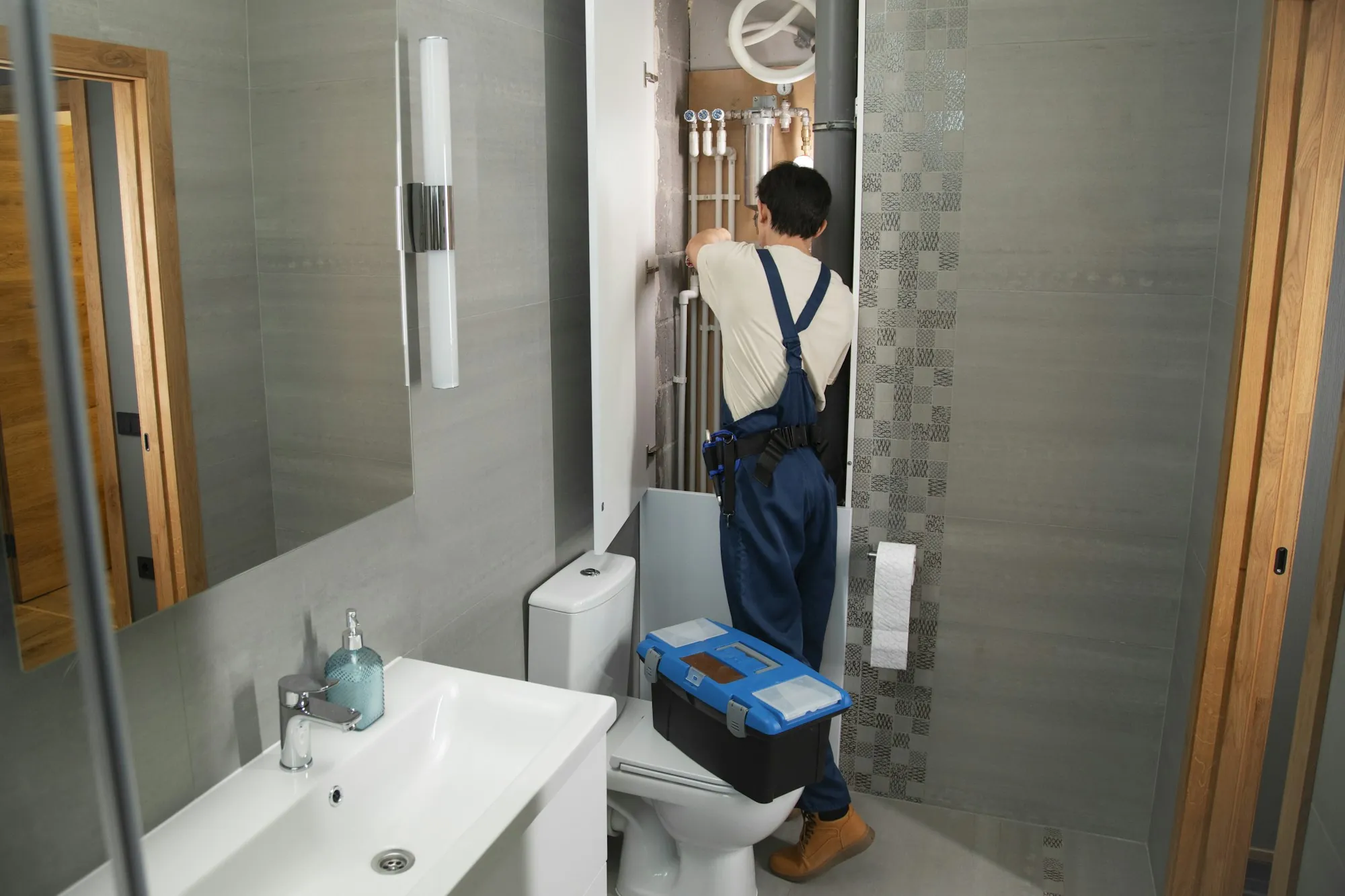 Local water specialists in Aliso Viejo Plumber with a toolbox working in a home bathroom