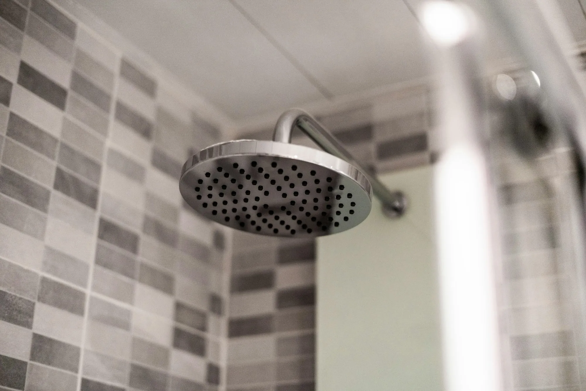 Stainless rain shower head in a tiled bathroom