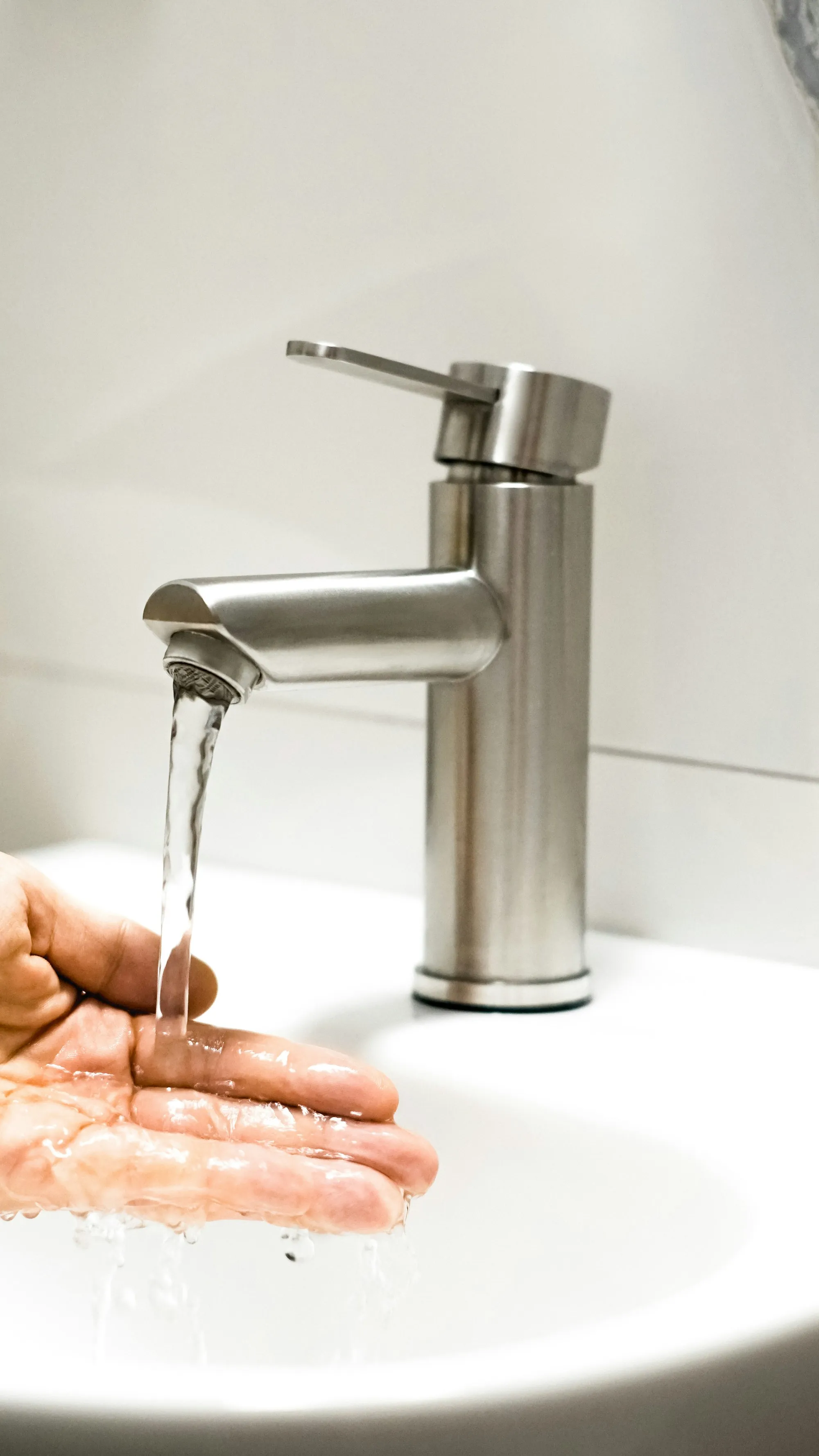 Salt-free water conditioners in Aliso Viejo Hand under water running from a brushed steel faucet