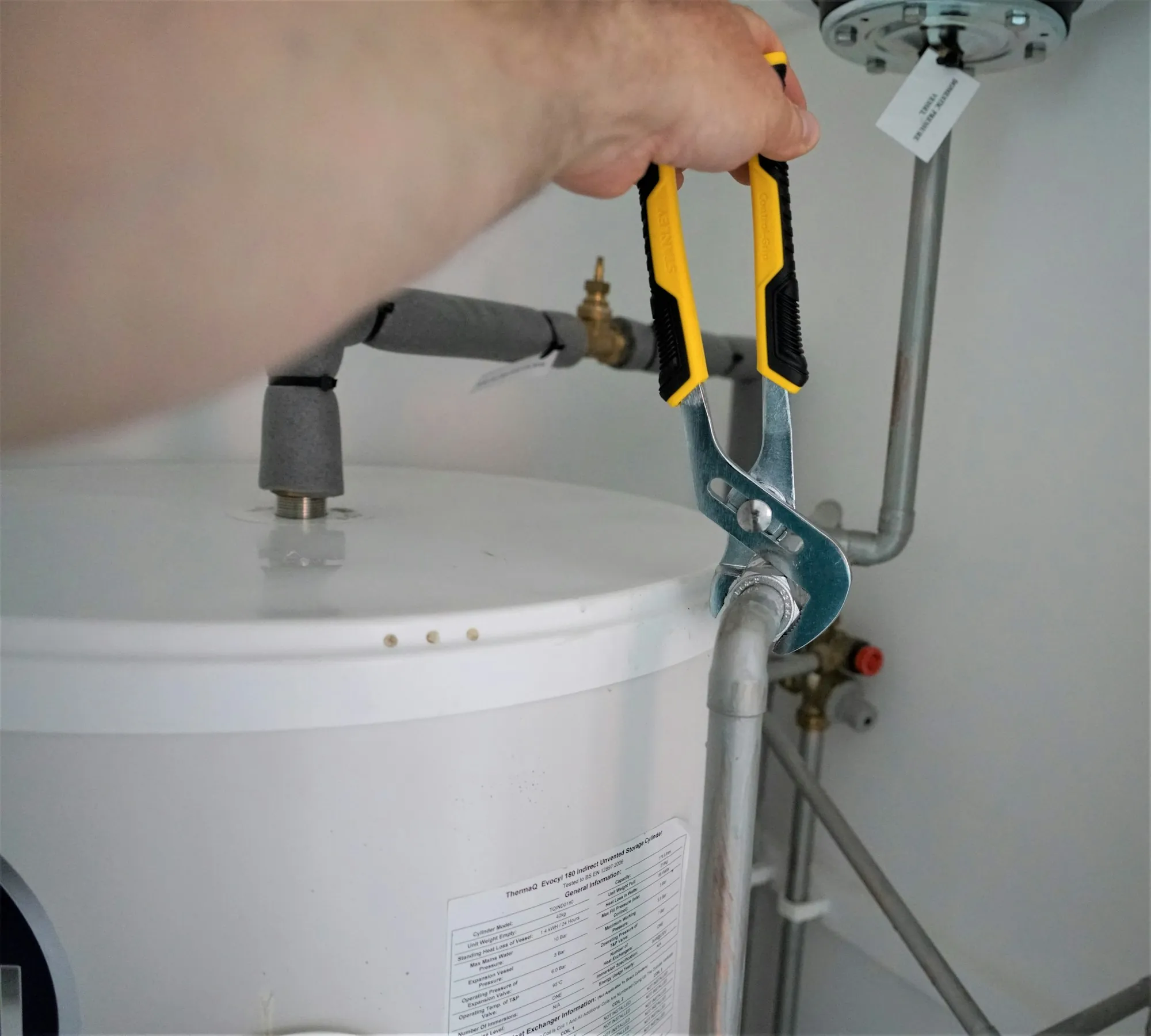 Scale prevention and water heater protection in Aliso Viejo Wrench on a pipe fitting at the top of a water heater